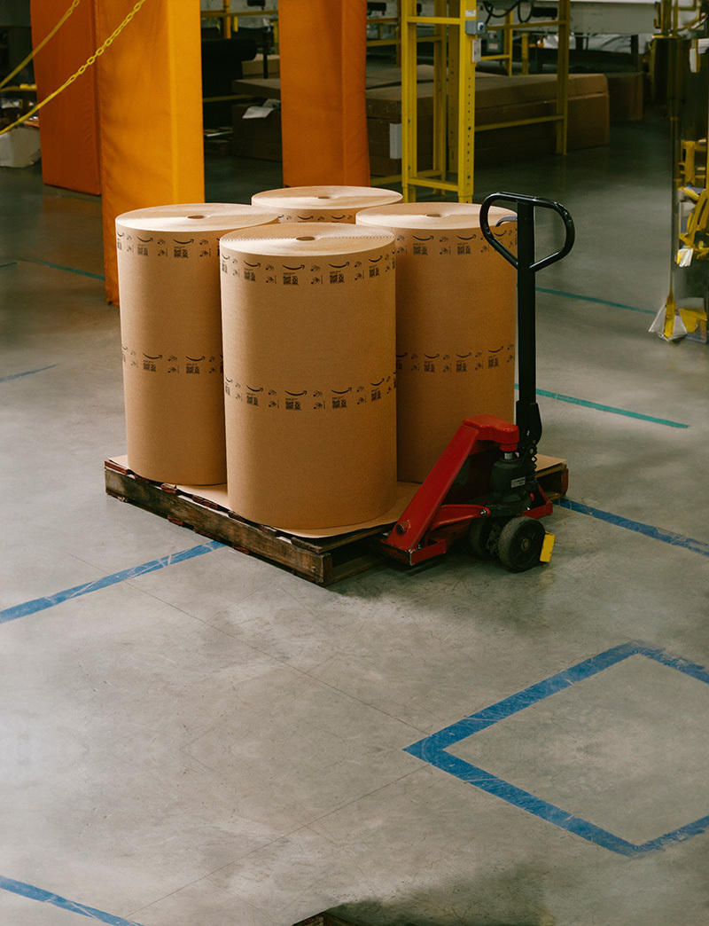 Four large rolls of paper material are shown on a pallet jack.