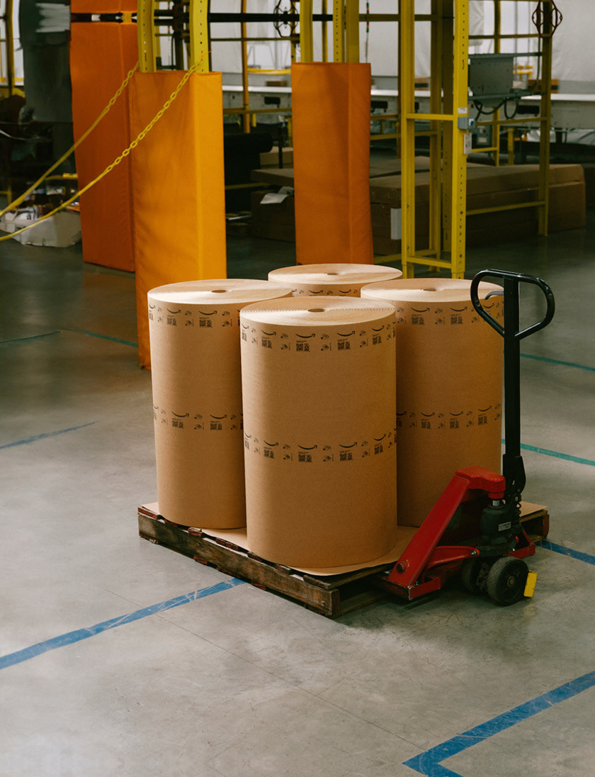 Four large rolls of paper material are shown on a pallet jack.