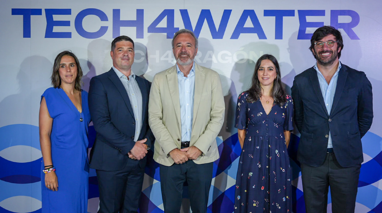 A group of five people stand for a photo in front of a background that says "TECH4WATER." 