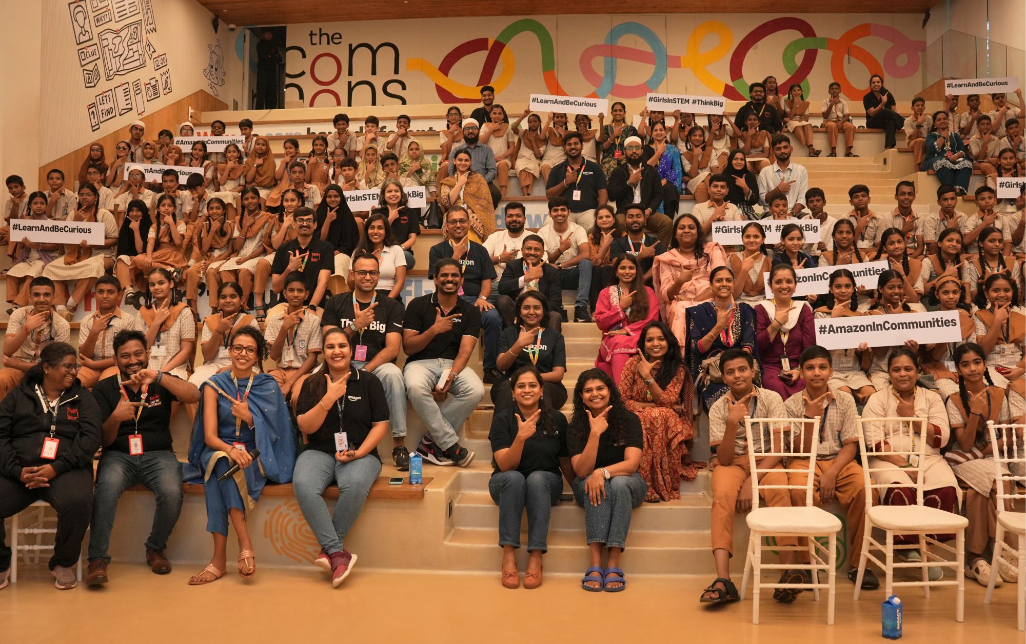 A large group photo of people smiling and holding signs. 