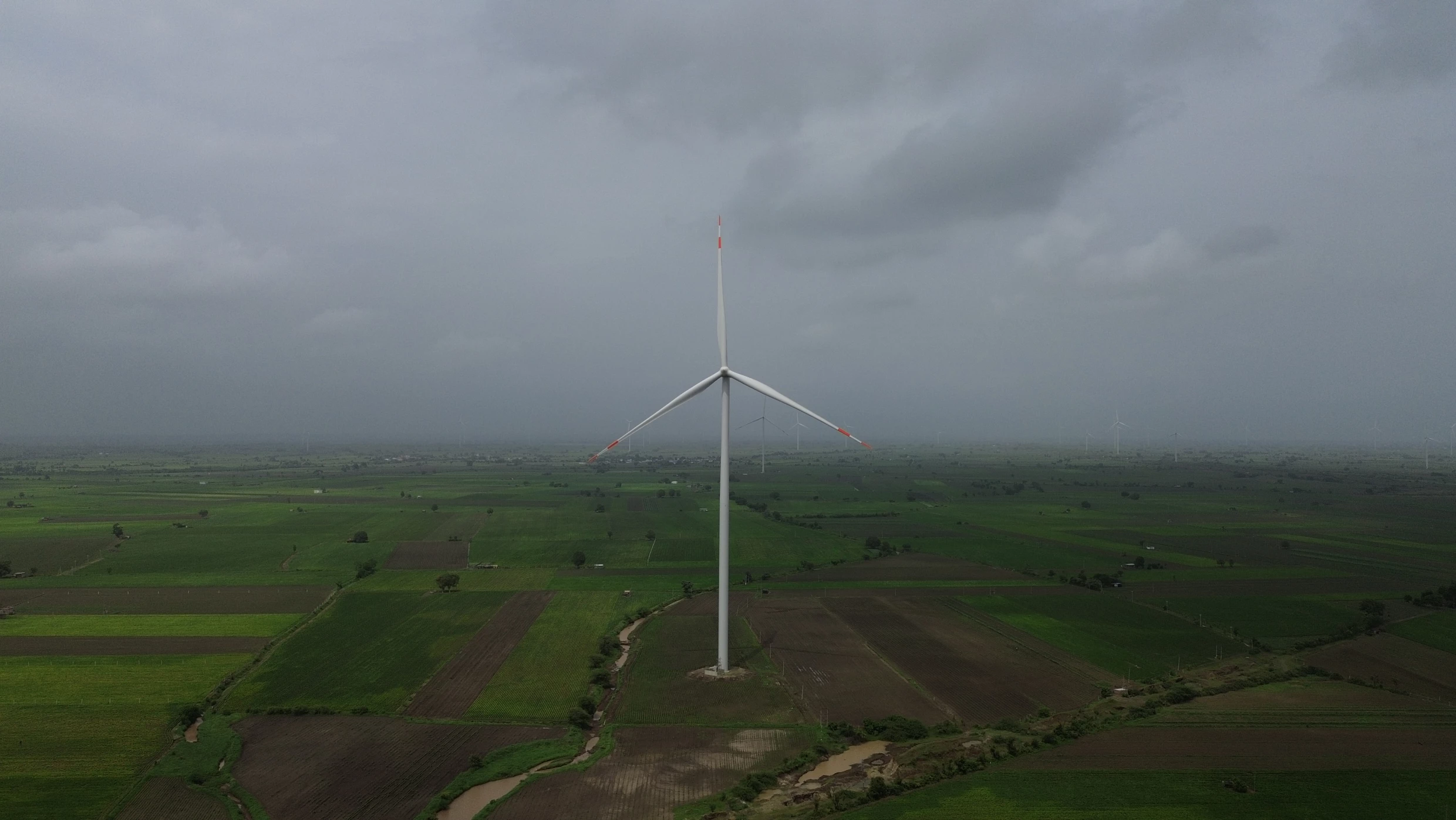 A wind turbine stands in green fields of farmland.