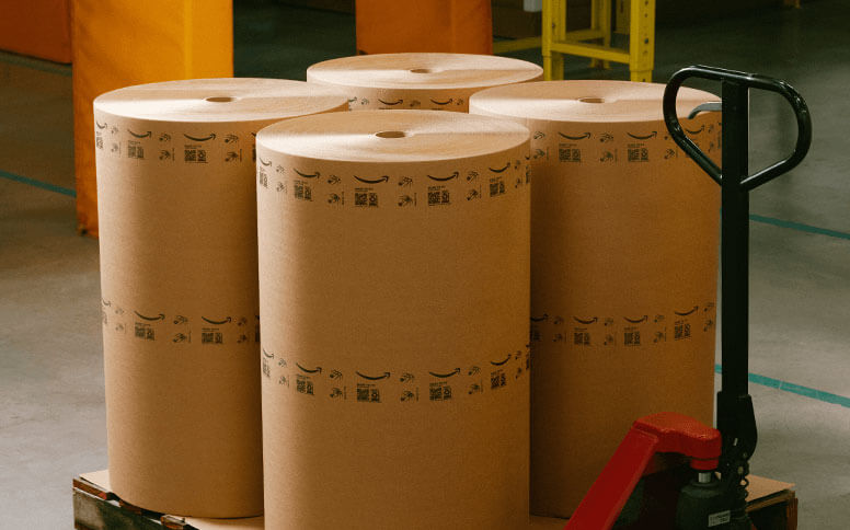 Four large rolls of paper material are shown on a pallet jack.