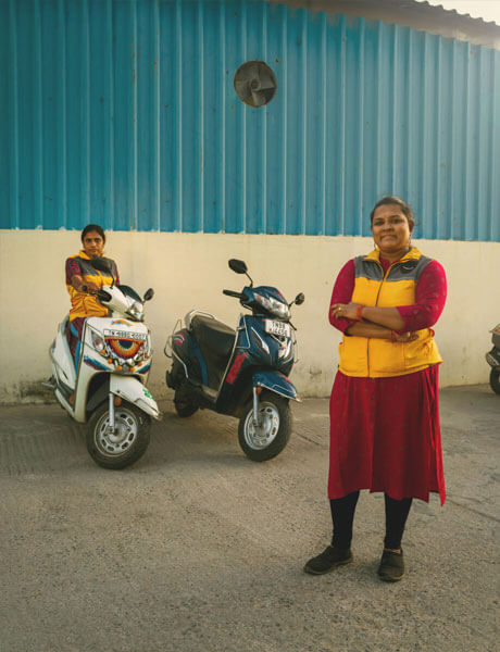 Two delivery drivers pose next to motor bikes.