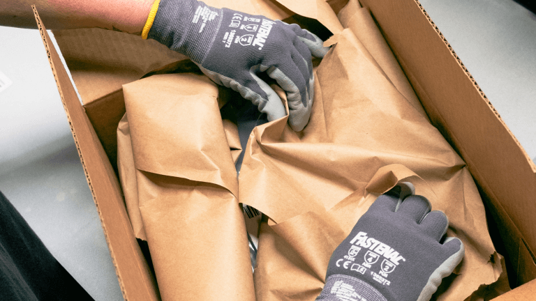 Employee using cardboard filling to pack amazon deliverables