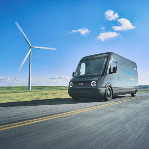 An Amazon electric delivery vehicle is shown driving past a wind turbine.