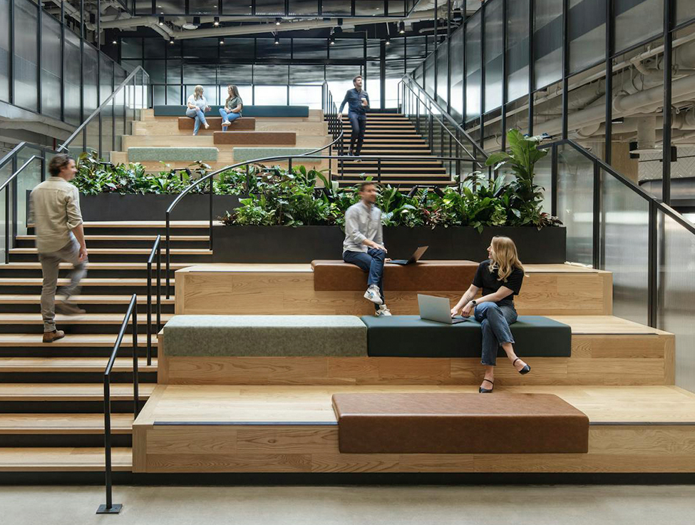 A stadium seating area with greenery and two people chatting.