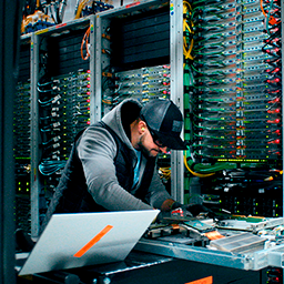 A person looks down over a piece of machinery in a data center.