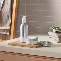 Body wash and body cream containers sit neatly on a bathroom sink countertop. 