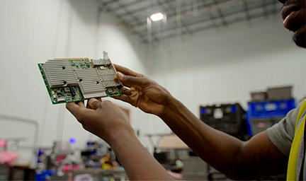 A person holds up a piece of decommissioned hardware. 