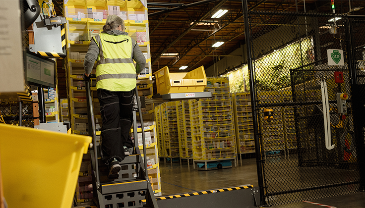 A person wearing a yellow safety vest climbs a ladder.