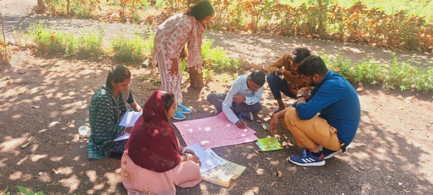 A small group sits on the ground together. 