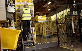 A person wearing a yellow safety vest climbs a ladder.