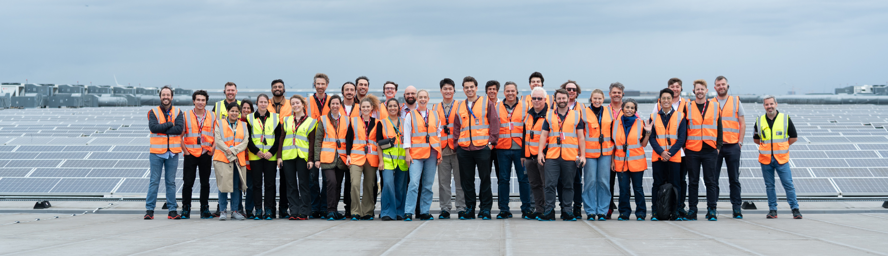 A large group of people in safety vests pose for a photo. 
