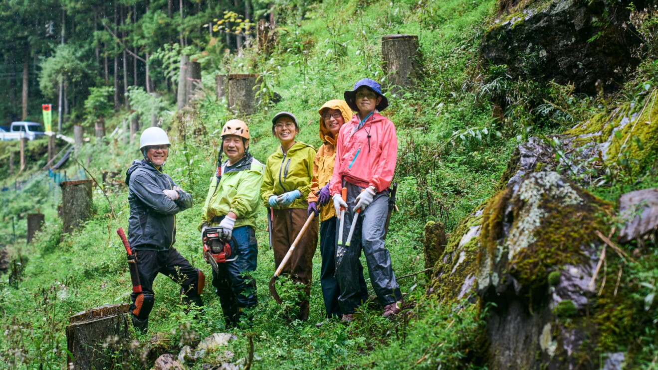 A group of people stand smiling in a forest.