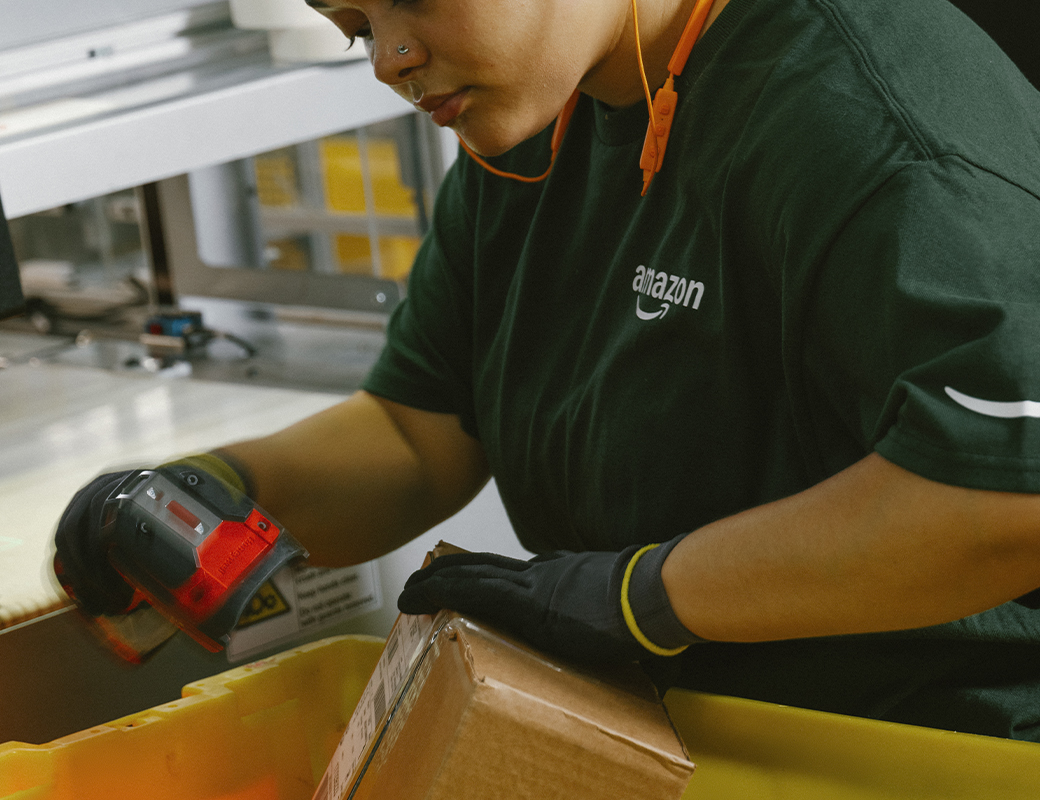 An Amazon employee is shown scanning a carboard.