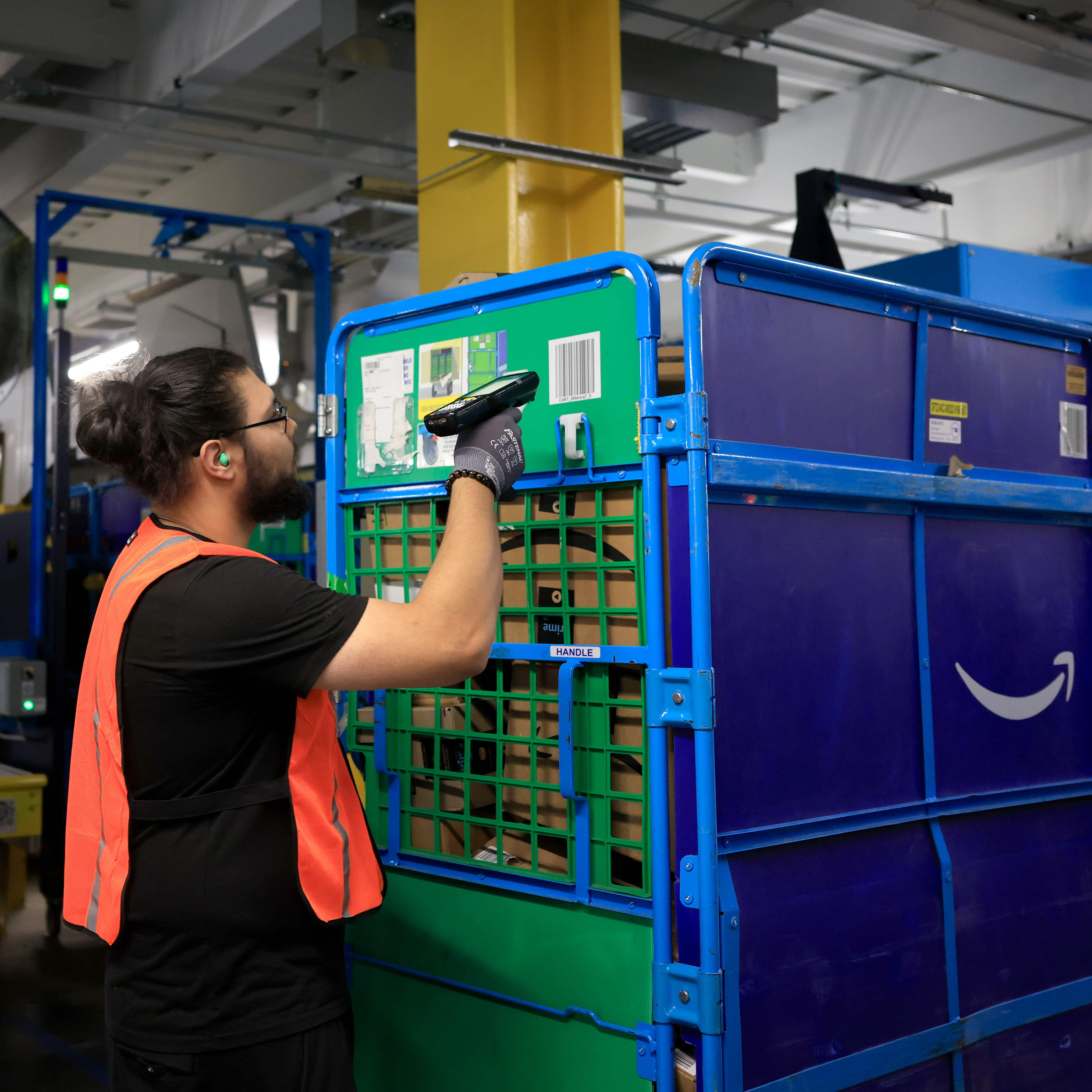 A person uses a handheld scanning device to scan labels on a crate of packages. 