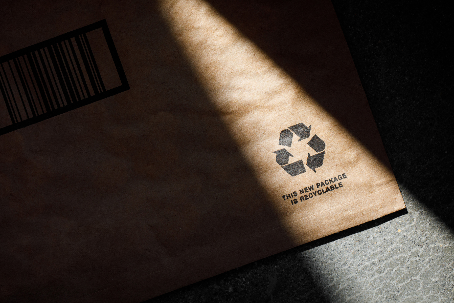 The sun illuminates the recycling logo on a paper mailer. 