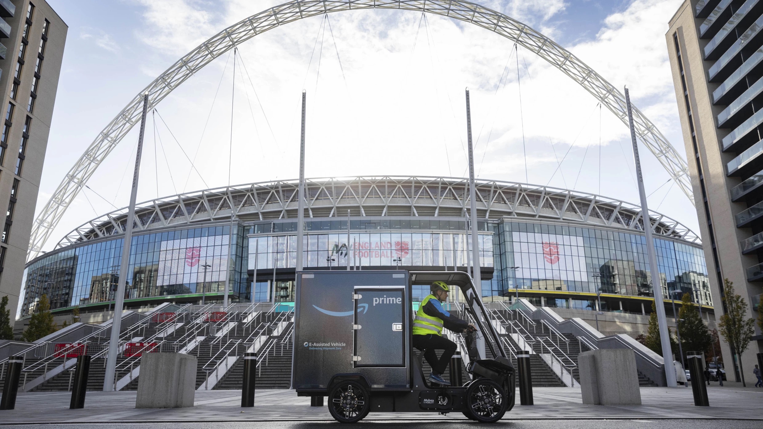 A person drives an e-bike delivery vehicle through a busy city street. 