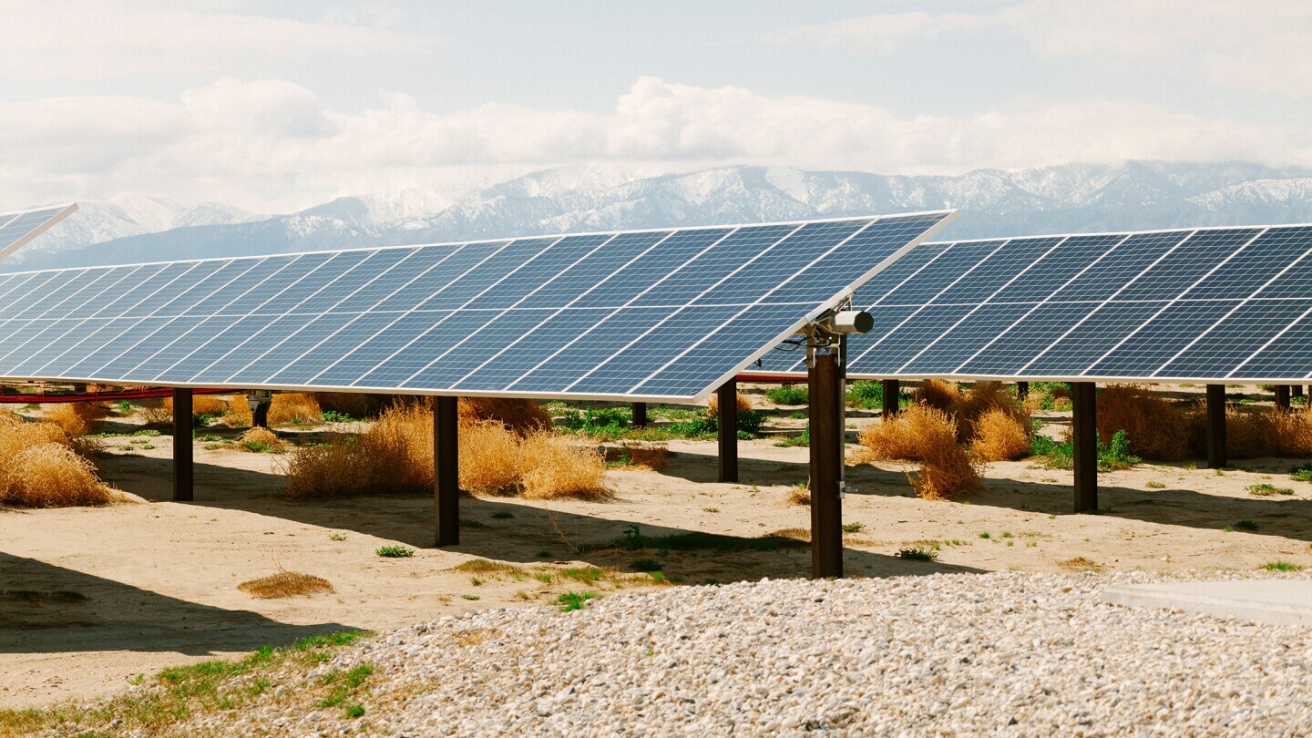 Rows of solar panels in a desert landscape. 