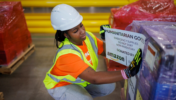 A person wearing safety equipment prepares a large shipment of emergency supplies. 