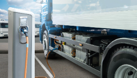 A long-haul truck plugged into a charger.  