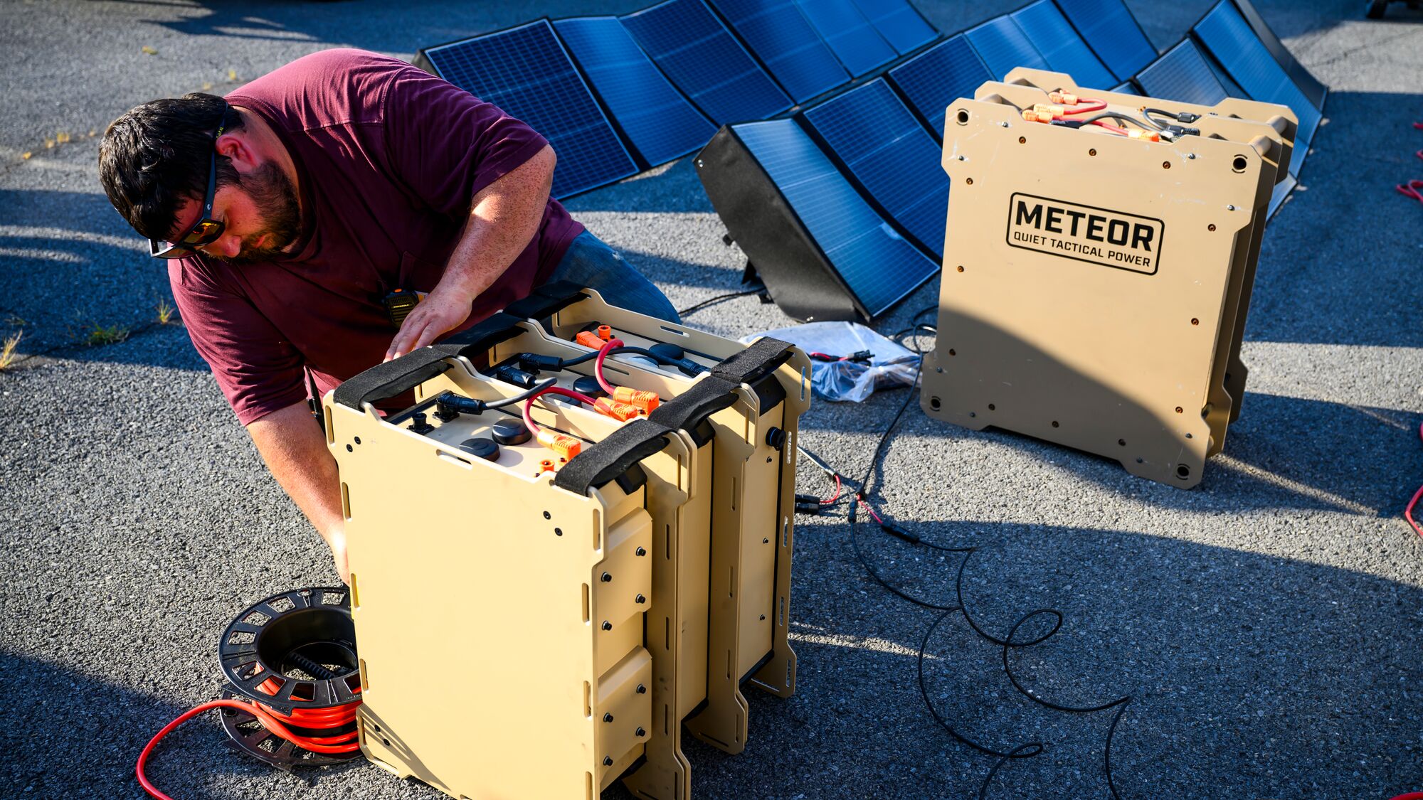 A person works on the ground with tactical power equipment boxes. 