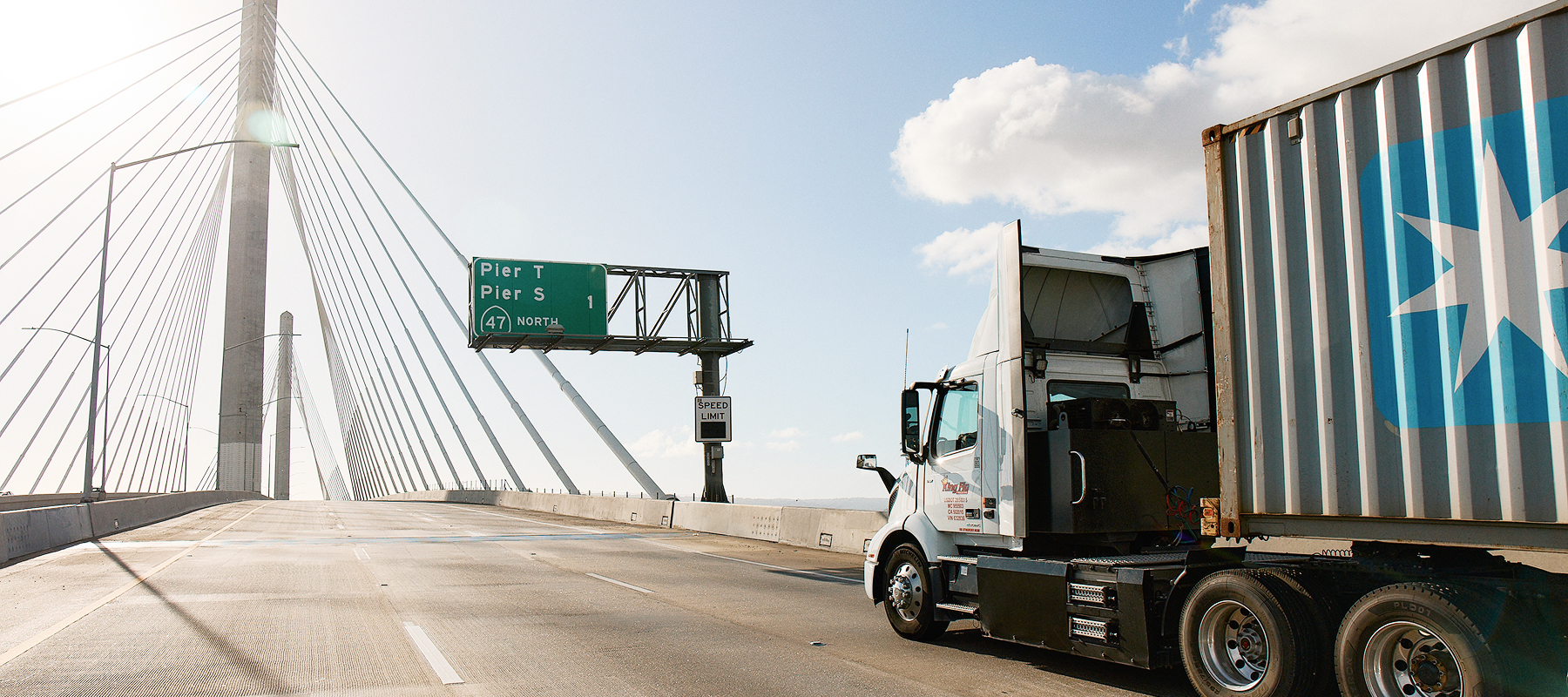 A side view of a long-haul truck driving on a bridge. 