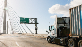 A side view of a long-haul truck driving on a bridge. 