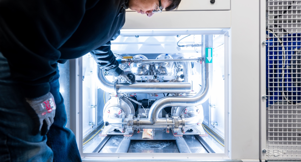 A person places their hand on a piece of metal machinery. 